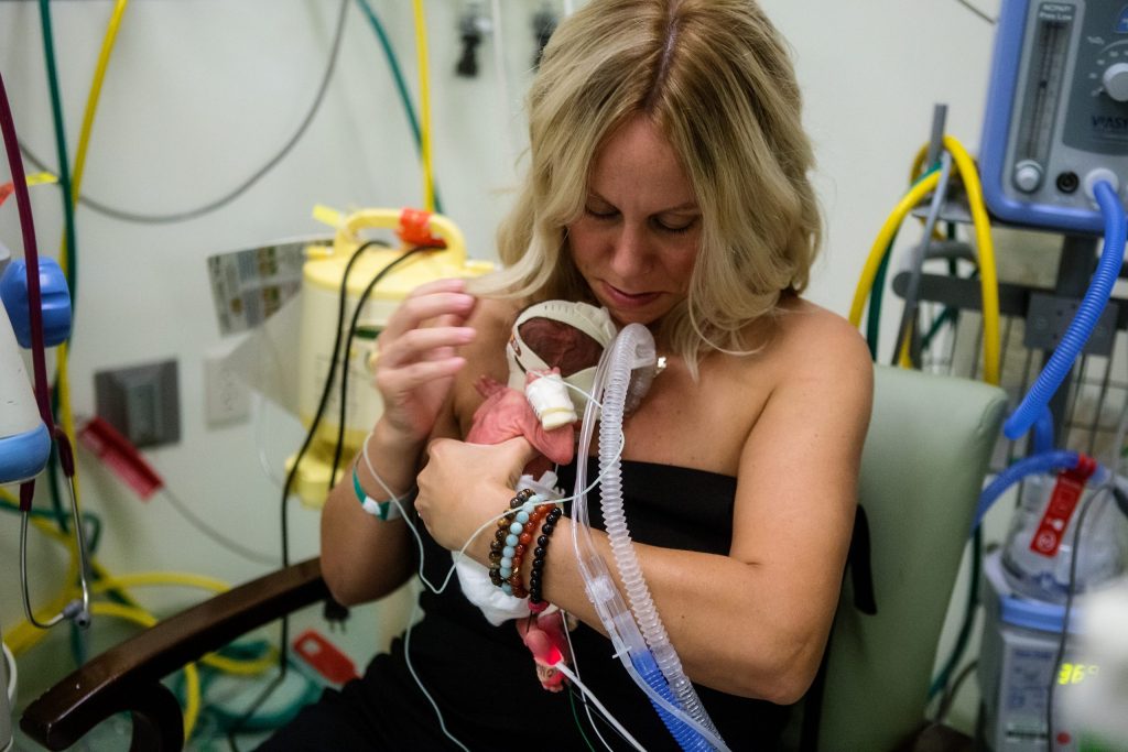 Lisa holding one of her newborn sons against her chest in the NICU