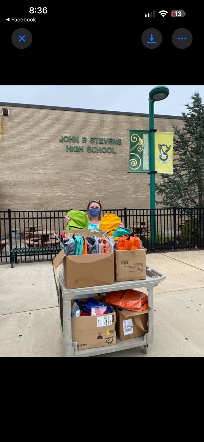 A school staff member with a cart of donated backpacks outside John P. Stevens High School